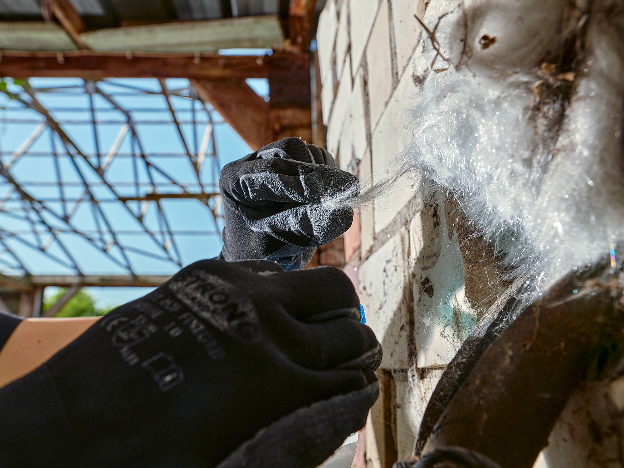 Ein Mitarbeiter nimmt Proben von künstlichen Fasern im Rahmen einer Asbestsanierung